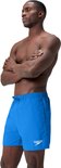 Short de bain bleu Speedo avec logo blanc, porté par un homme les bras croisés.