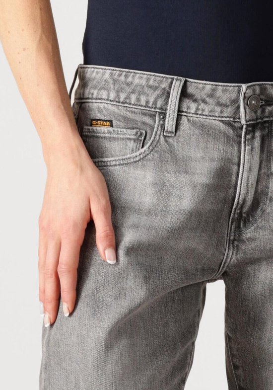 Vrouw draagt een grijze G-Star jeans met 'G-Star Originals' label op de zak.
