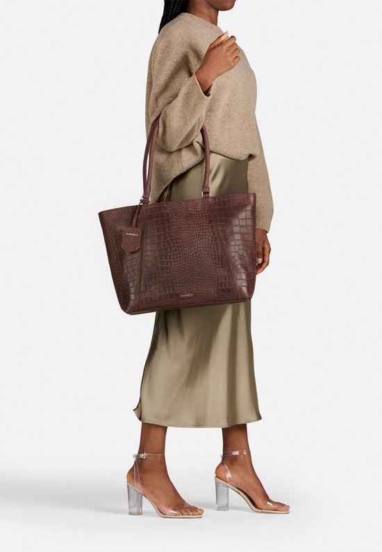 Model draagt een bruine Burkely tas met krokodillenprint, inclusief bijpassende tag en merklogo.