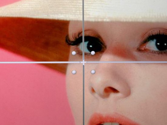 Gros plan des yeux, cils, nez et bouche d'Audrey Hepburn, avec un chapeau de paille et un nœud rose.