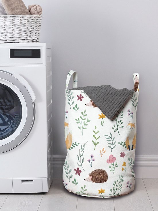 Wasmand met vosjes, egeltjes en bloemenprint in zachte kleuren. Naast een witte wasmachine.