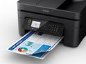 Zwarte Epson printer drukt een document af met grafieken, naast het apparaat ligt een papier met tekst.