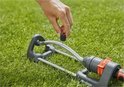 Hand plaatst een zwarte dop op de zwenksproeier van Gardena.