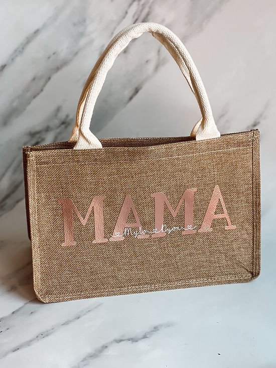 Sac brun en jute avec poignées en corde. Sur le devant, "MAMA" est écrit en lettres roses brillantes, suivi de "Mylo & Owen" en plus petit.