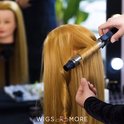 Een oefenhoofd met lang blond haar wordt gekruld met een krultang.