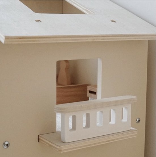 Buitenste muur van een houten poppenhuis met raam en wit balkonhek.