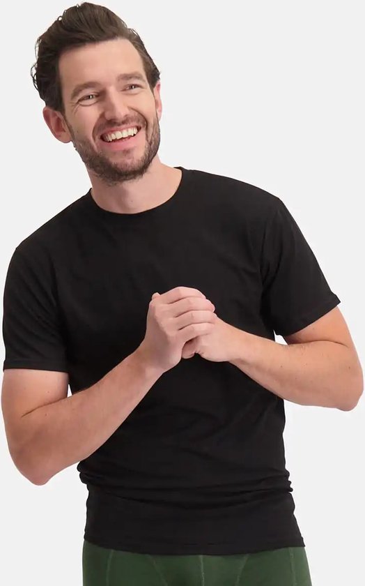 Een lachende man in een zwart T-shirt met ronde hals en een groene onderbroek.