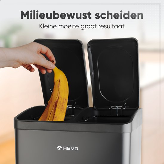 Hand doet een bananenschil in een vak van de zwarte prullenbak met twee compartimenten.