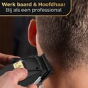 Close-up van een zwarte tondeuse die het haar van een man achter zijn nek trimt.