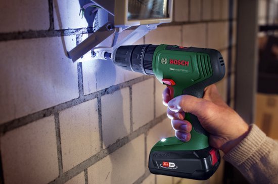 Groene en zwarte Bosch EasyImpact 18V-40 accuboormachine met een rode schakelaar, gebruikt om in een stenen muur te boren.