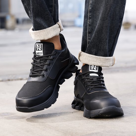 Zicht op de voeten in zwarte werksneakers met veters, mesh bovenkant en robuuste zool.