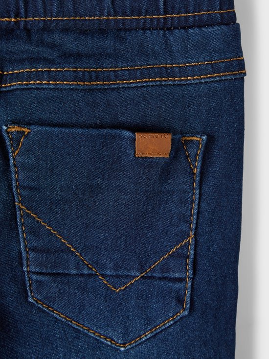 Detail achterzak spijkerbroek met naamlabel.