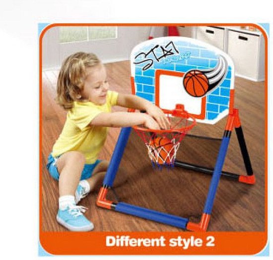 Een jong meisje in een geel shirt en blauwe shorts speelt met een basketbalset. Het bord is wit met blauwe bakstenen en de tekst 'STA'.