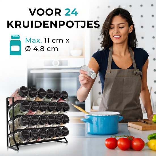 Vrouw met schort die een kruidenpotje strooit in een keuken, met een kruidenrek gevuld met 24 potjes.