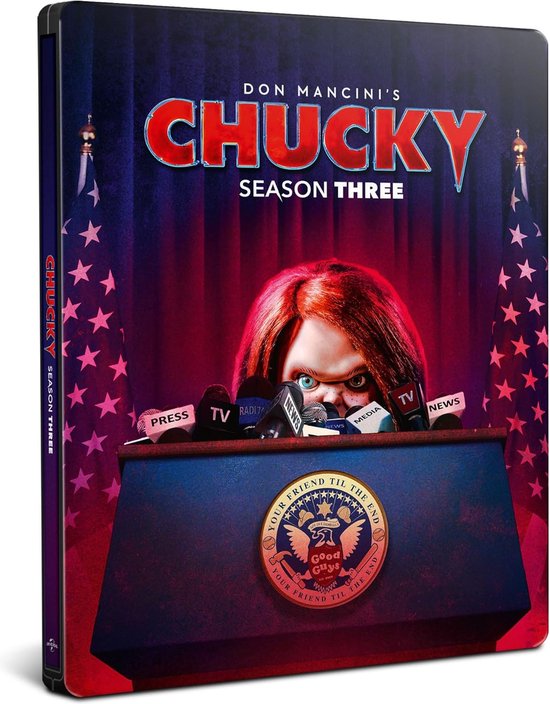 Steelbook met Chucky's gezicht achter een persconferentie-lessenaar met microfoons en Amerikaanse vlaggen.