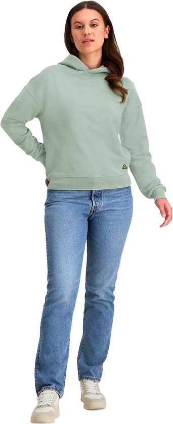 Model in een mintgroene NOMAD hoodie met jeans op een witte achtergrond.