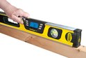 Hand houdt een gele Stanley FatMax waterpas op een houten balk.