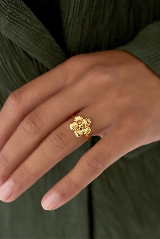 Goudkleurige ring met bloemendetail, gedragen door een vrouw.
