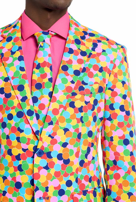 Een felgekleurd kostuum met een print vanconfetti, gedragen over een roze overhemd en stropdas.