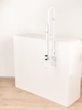 Opklapbare witte toiletbeugel met steunpoot, tentoongesteld op een witte kubus.