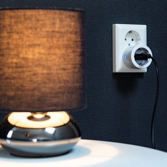 Wit slimme stekker in een stopcontact met een lamp ernaast.