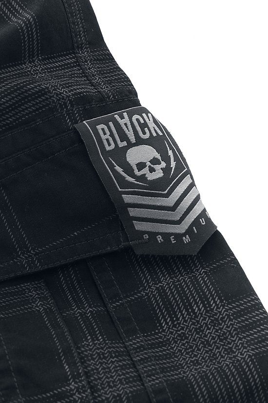 Detail van een zwarte cargobroek met ruitjesprint en 'BLVCK PREMIUM' patch met schedel.