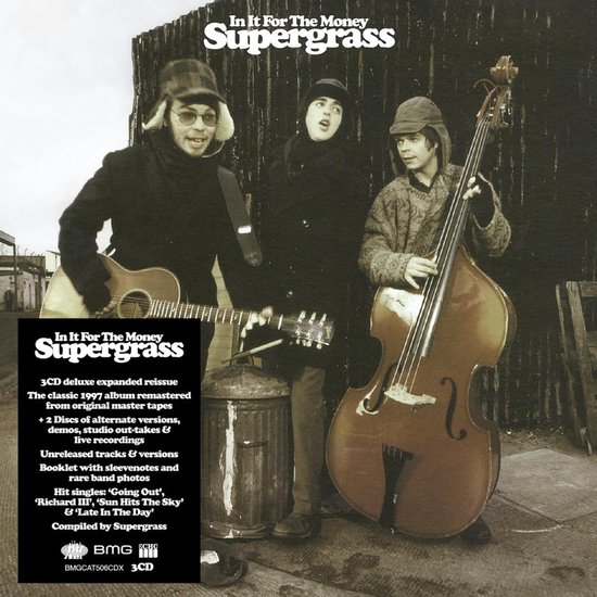 Drie mannen in winterkleding poseren met instrumenten. Links een man met gitaar, in het midden een man met kleine gitaar, rechts een man met contrabas.