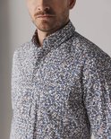 Detailopname van een overhemd met een print van witte, bruine en donkerblauwe lijnen.
