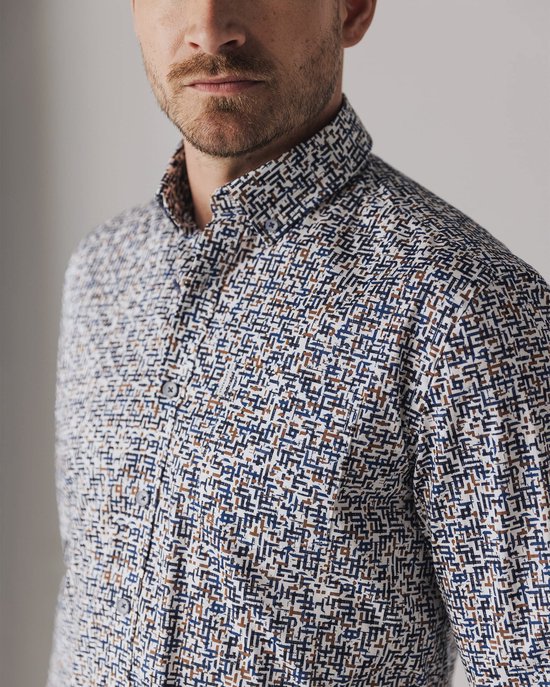 Detailopname van een overhemd met een print van witte, bruine en donkerblauwe lijnen.