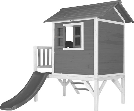 Wit en grijs houten speelhuis op palen met veranda, trap en een glijbaan aan de zijkant.