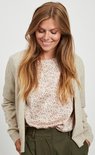 Model met blonde haren draagt een beige gebreid vest over een bloemenprint top.