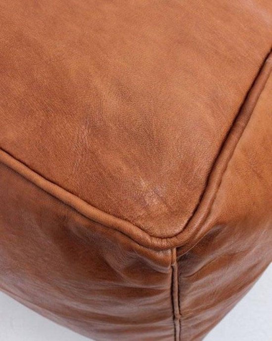 Close-up van de hoek van een bruine leren poef.