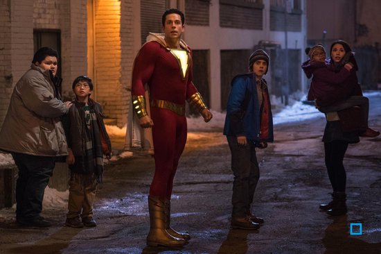 Shazam staat op een straat met meerdere kinderen om hem heen, die naar hem kijken.
