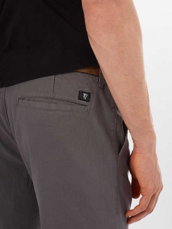 Detail van achterzak met logo label op grijze chino broek.