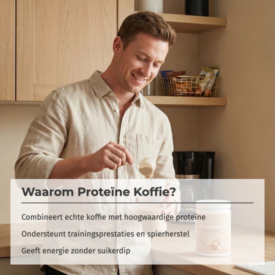 Een man in een beige hemd doet eiwitpoeder uit een schepje in een pot Naturecan proteïne koffie, in een keuken.