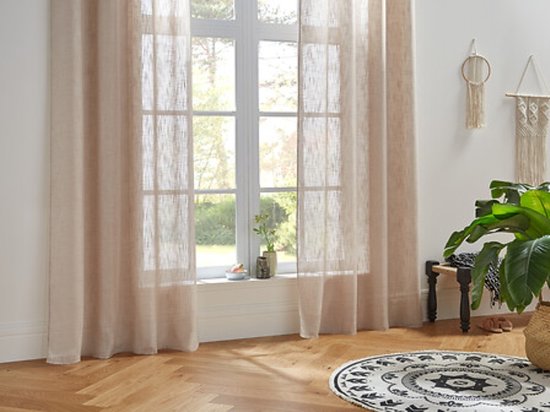 Lichte, beige vitrage gordijnen met subtiele textuur hangen voor een raam.