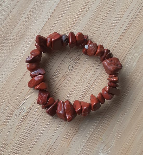 Armband van onbewerkte rode jaspis steentjes op een houten ondergrond.