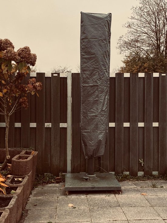 Grijze parasolhoes staand voor een parasol in de tuin.