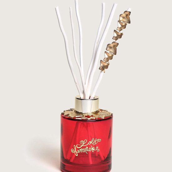 Rode glazen geurverspreider met gouden details, witte stokjes en een gouden sterrenhanger. Lolita Lempicka "Sweet Bijou".
