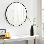 Ronde spiegel met zwart frame aan een witte muur boven een console met kaarsen en vaas.