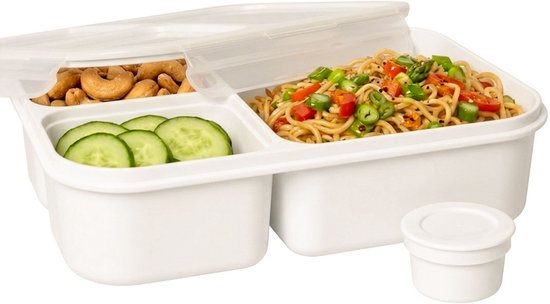 Boîte à lunch blanche à trois compartiments. Remplie de noix de cajou, rondelles de concombre et nouilles aux légumes.