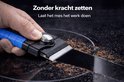 Blauwe schraper met metalen mes maakt een krasloze streep door aangebrand vuil op een zwarte kookplaat.