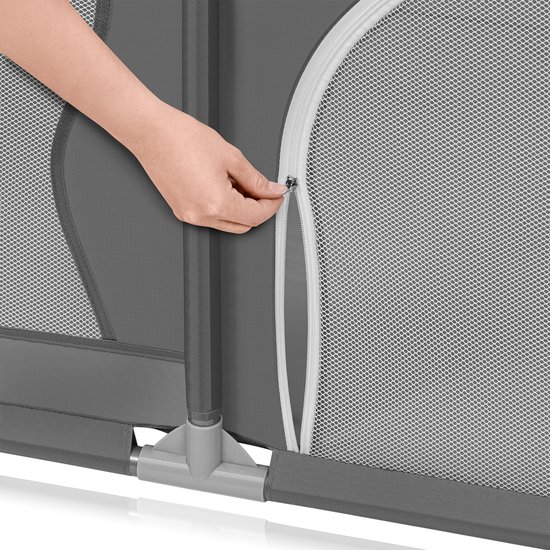 Hand die een rits opent op een grijze babybox van Lionelo met gaaspaneel.