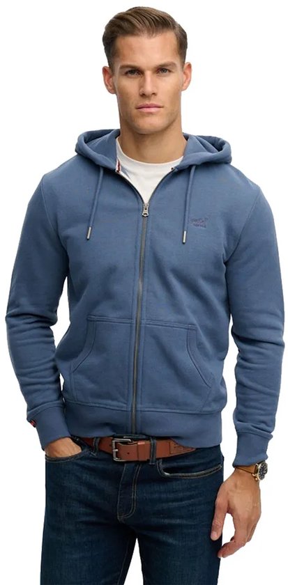 Man met blauwe Superdry hoodie met rits, witte t-shirt, spijkerbroek en bruine riem.