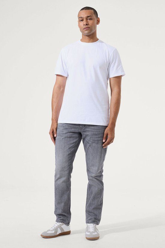 Man, van voren gezien, draagt een grijze slim fit jeans met een witte t-shirt.