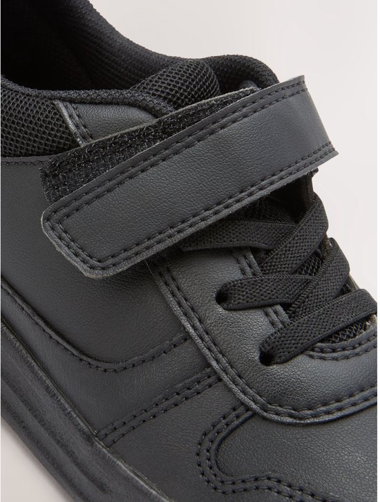 Close-up van de voorkant van een zwarte sneaker met klittenbandsluiting en elastische veters.