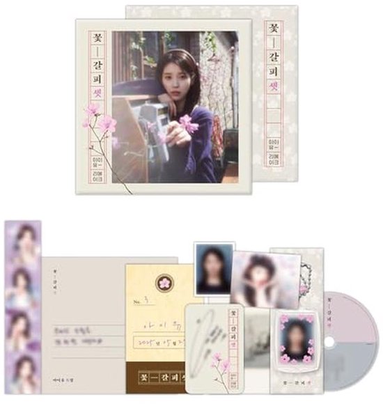 Couverture d'album avec une femme tenant un appareil photo, à côté d'un CD, de cartes photo, d'un marque-page, de feuilles d'autocollants et d'une étiquette.