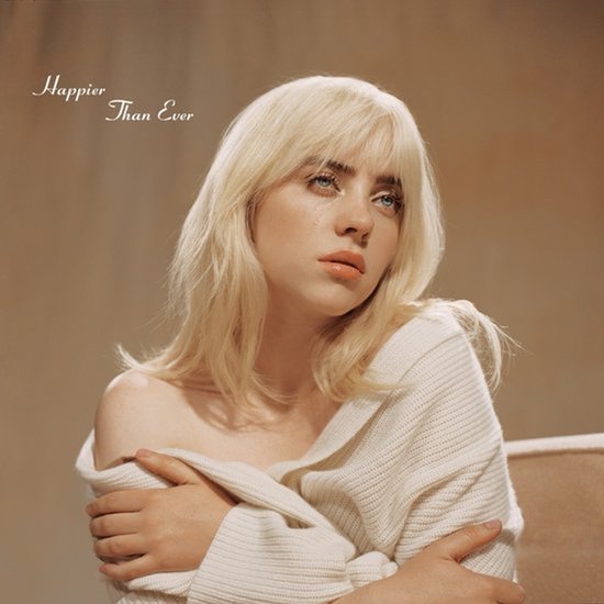 Billie Eilish met blond haar, draagt een off-white gebreide trui, met de tekst 'Happier Than Ever'.