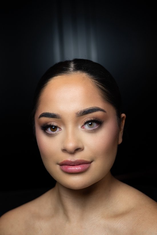 Model met een naturel make-up die een grijs/groene kleurlens in haar linkeroog draagt. Haar rechteroog heeft haar natuurlijke bruine kleur.