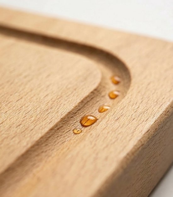 Close-up van waterdruppels in de sapgeul van een houten snijplank.